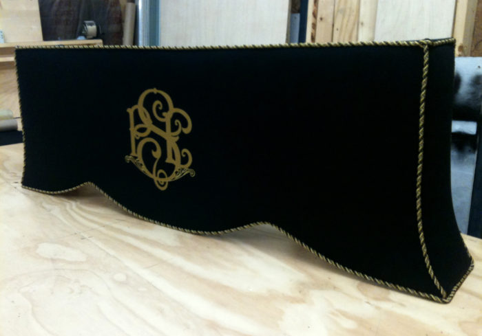 Dark custom cornice board with yellow-gold emblem in center