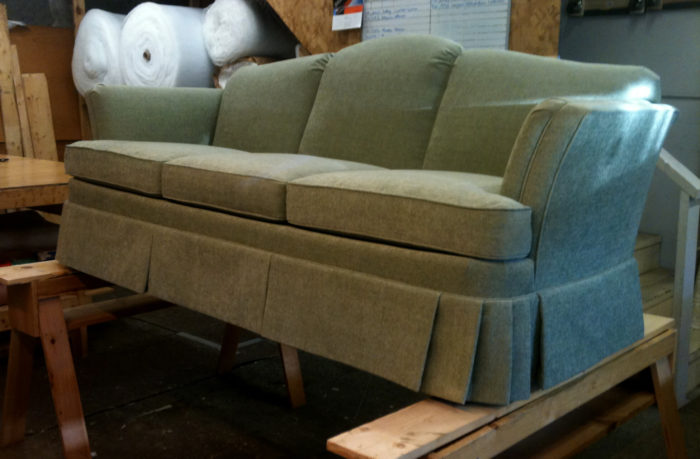 Finished green sofa from Quincy, propped up on two wooden beams